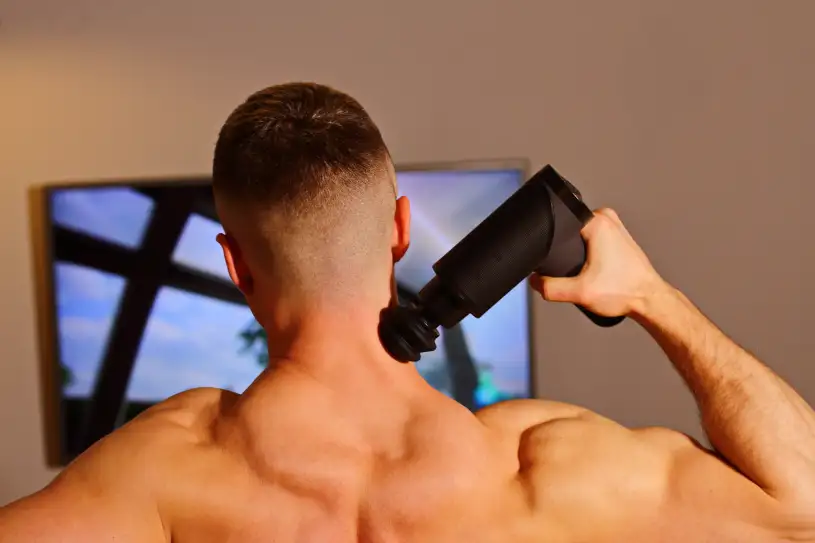 afbeelding van een man die een massage gun gebruikt bij spierpijn